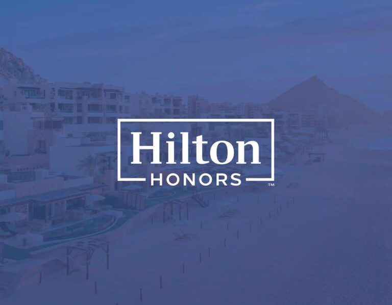 Hilton Honors loyalty program official banner featuring a luxurious beachfront resort at dusk with the Hilton Honors logo prominently overlaid