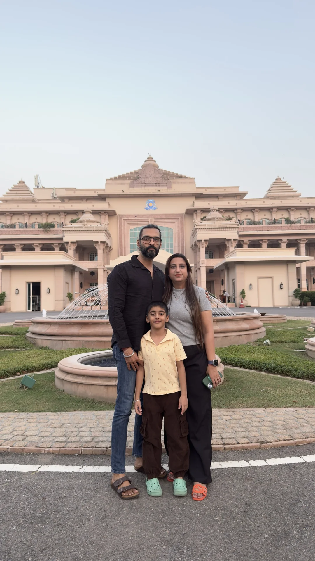 Family of three in front of ITC Grand Bharat palace building on a points-funded stay