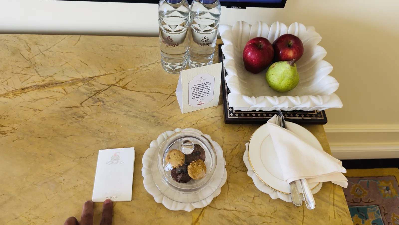 In-room welcome amenity at The Leela Palace New Delhi with flourless cookies, apples, a pear and bottled water