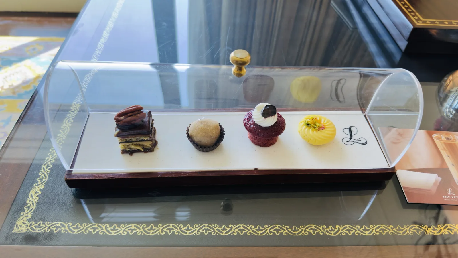 Welcome desserts at The Leela Palace New Delhi: pecan opera cake, laddoo, red velvet cupcake and kesar peda under a glass dome